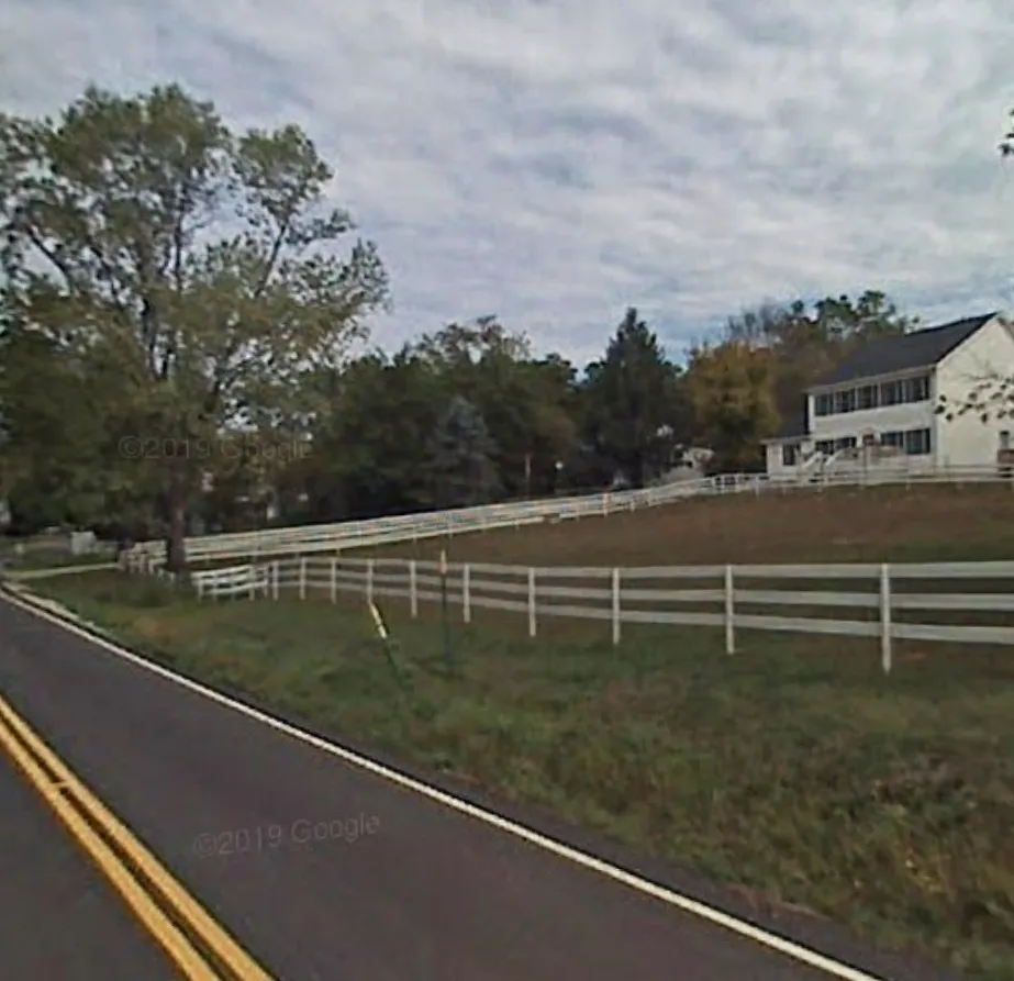 farm house with a white fence on a country road