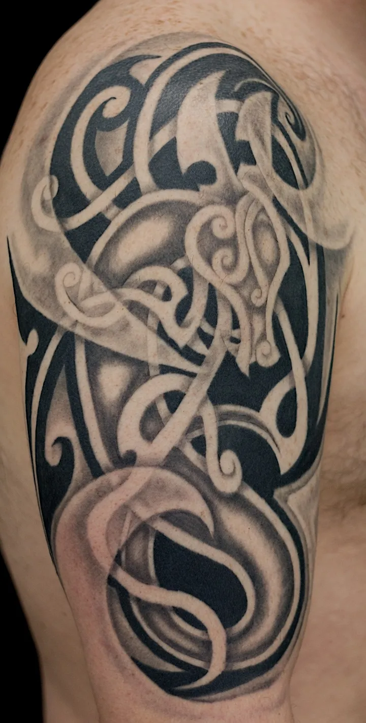 Black and grey ornamental lettering tattoo with interwoven flowing strokes