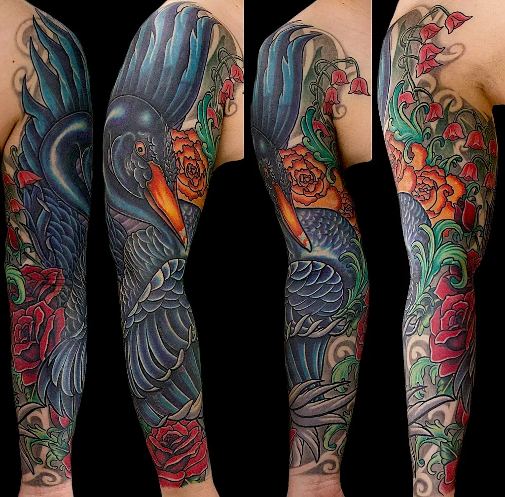 Color tattoo sleeve with a large blue bird, flowers, and flowing waves