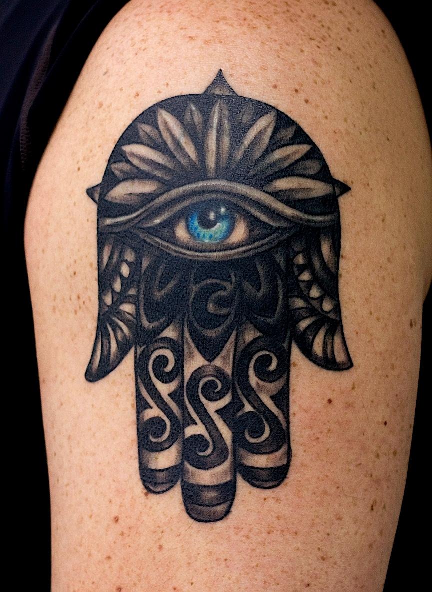 Black ornamental hamsa hand tattoo with a blue eye