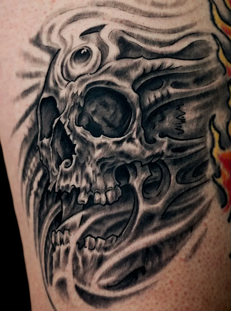 Black and grey biomechanical skull tattoo with flowing skeletal details