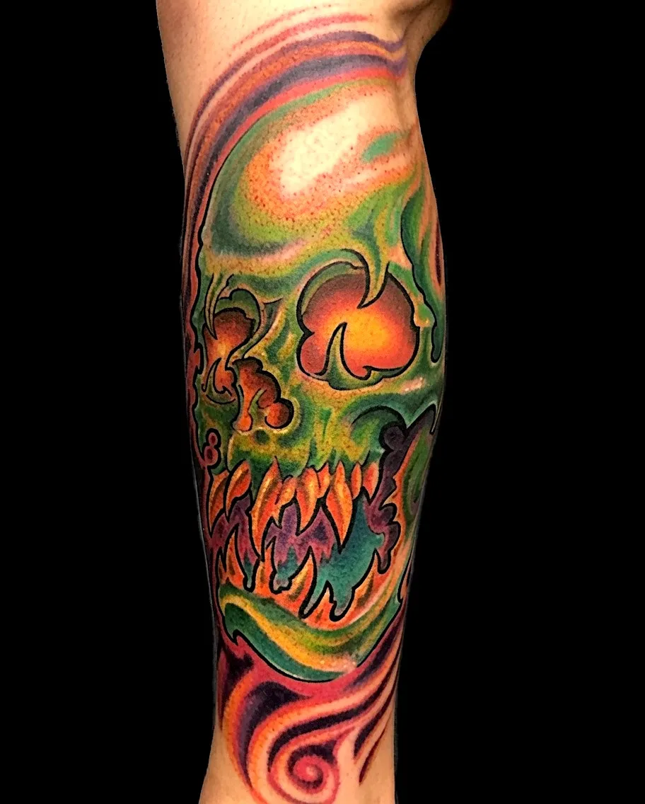 Green skull tattoo with orange flames and flowing warm-colored patterns