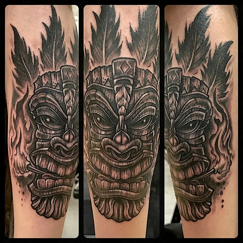 Black and grey tiki mask tattoo surrounded by flames