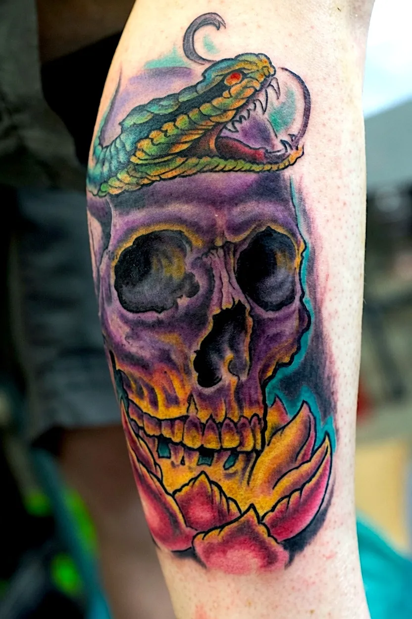 Purple skull tattoo with a green snake, crescent moon, and pink flower