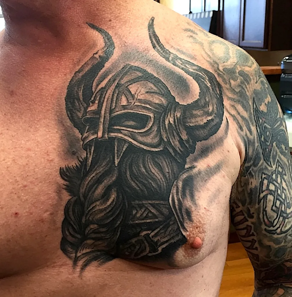 Black and grey bearded Viking portrait tattoo with a horned helmet