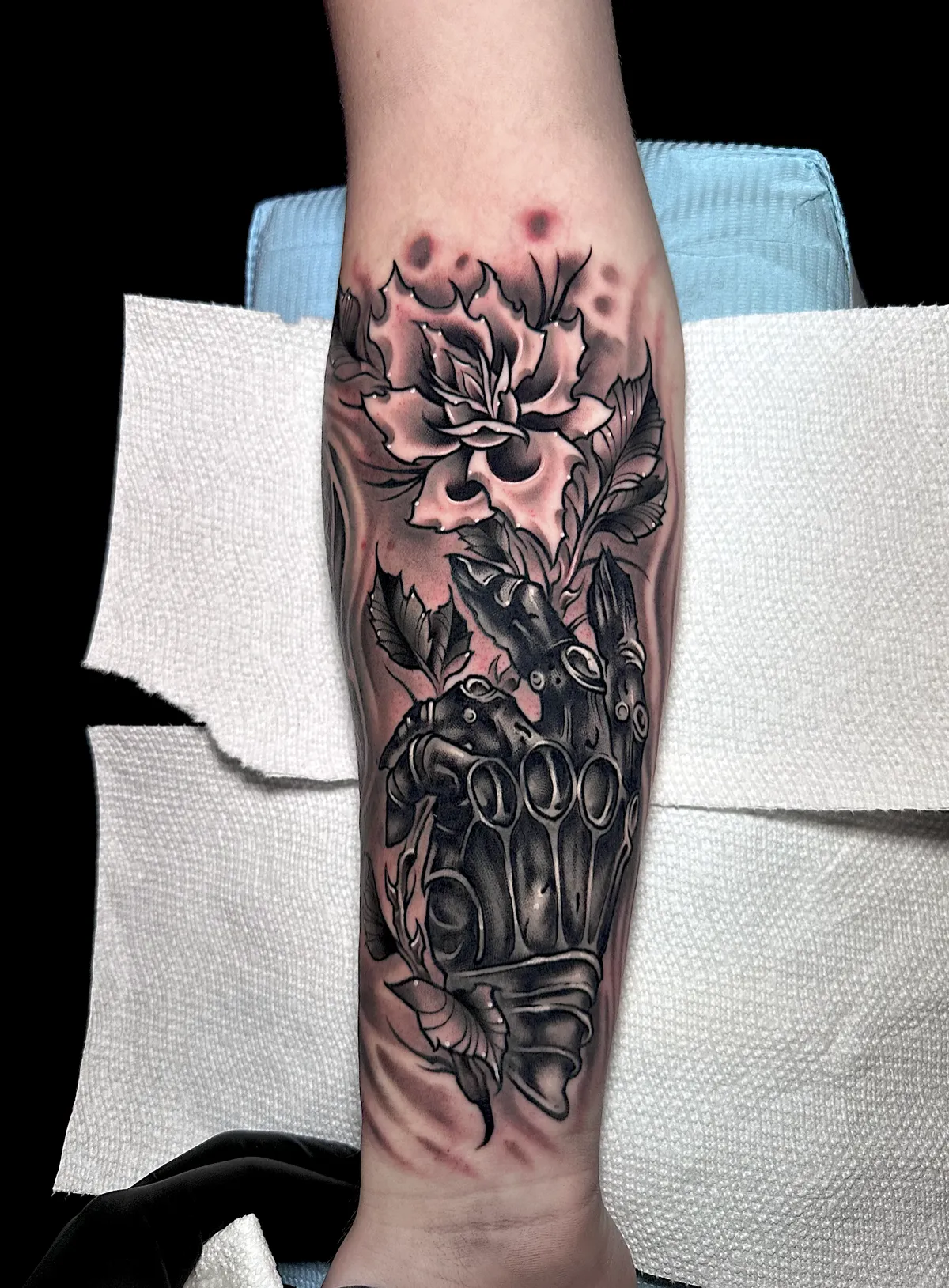 Black and grey lotus and armored mask tattoo on the forearm