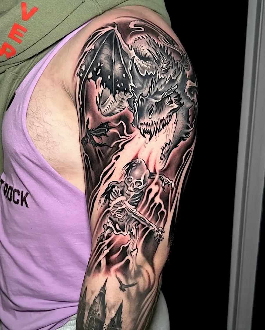 Black and grey fantasy tattoo sleeve with skulls, a dragon, and an armored figure