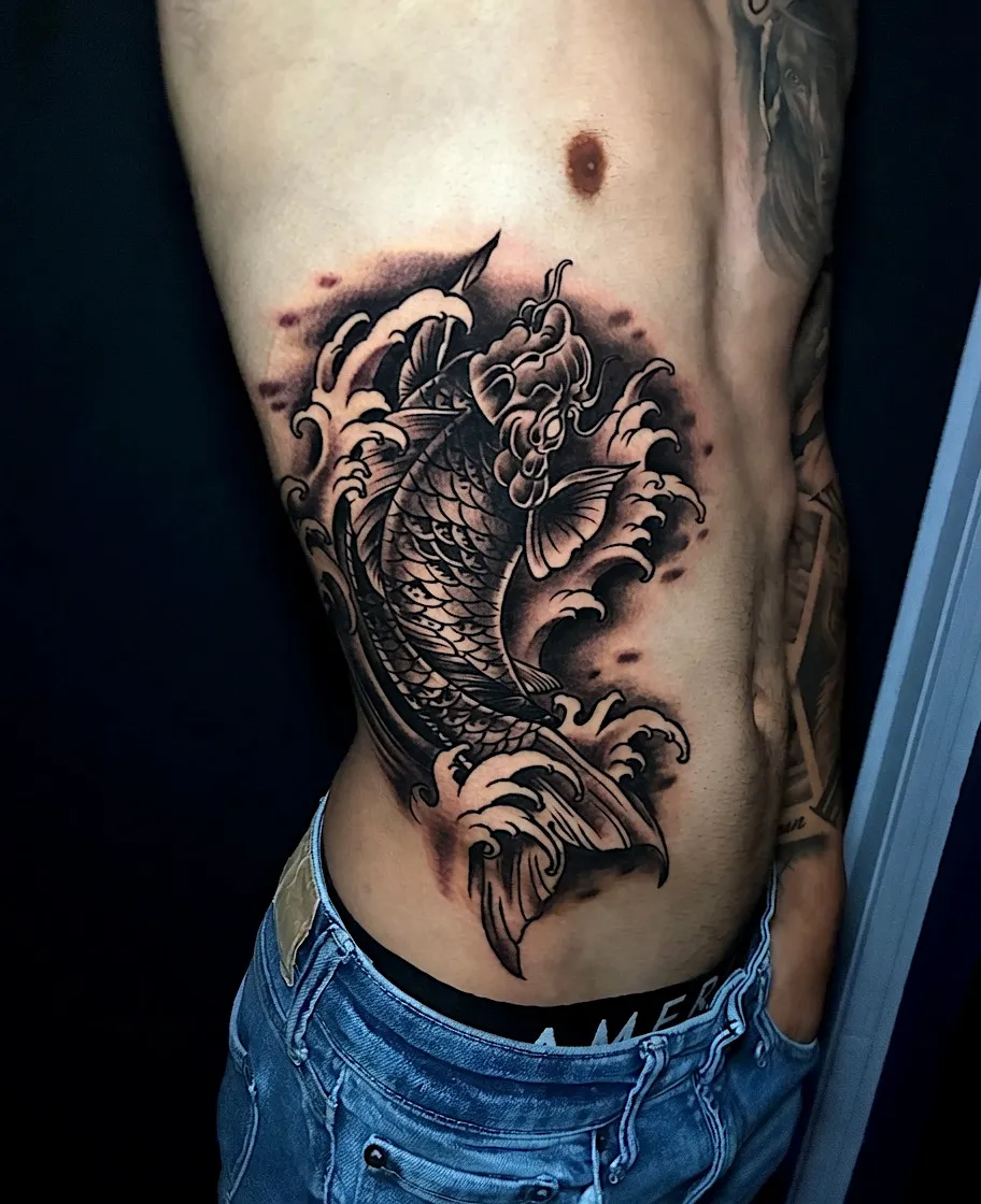 Black and grey koi fish tattoo with flowers on the ribs