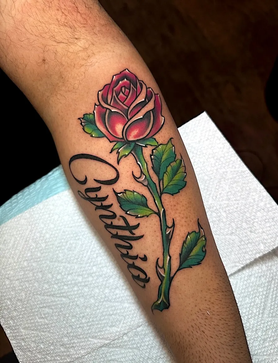 Red rose tattoo with green leaves and the name Cynthia