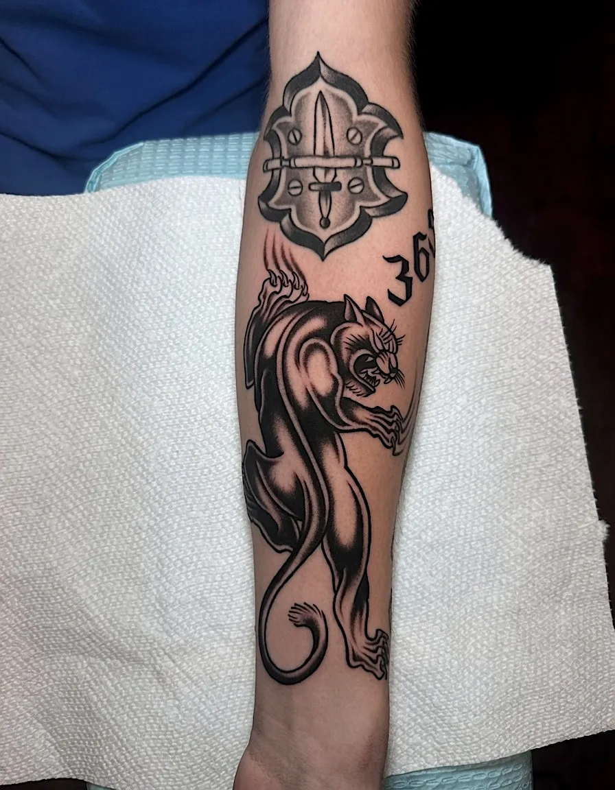 Black and grey panther tattoo with a fire-service emblem