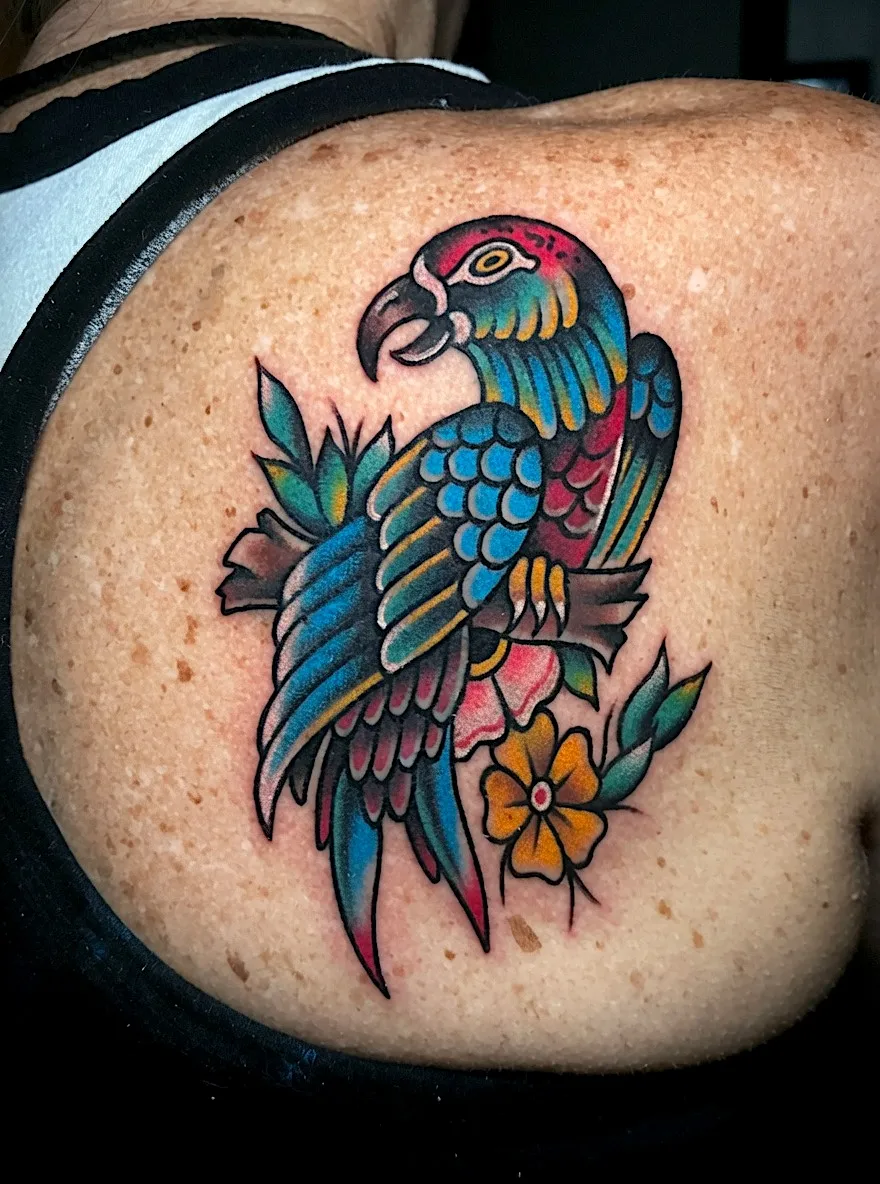 Color parrot tattoo with blue and green feathers and a yellow flower