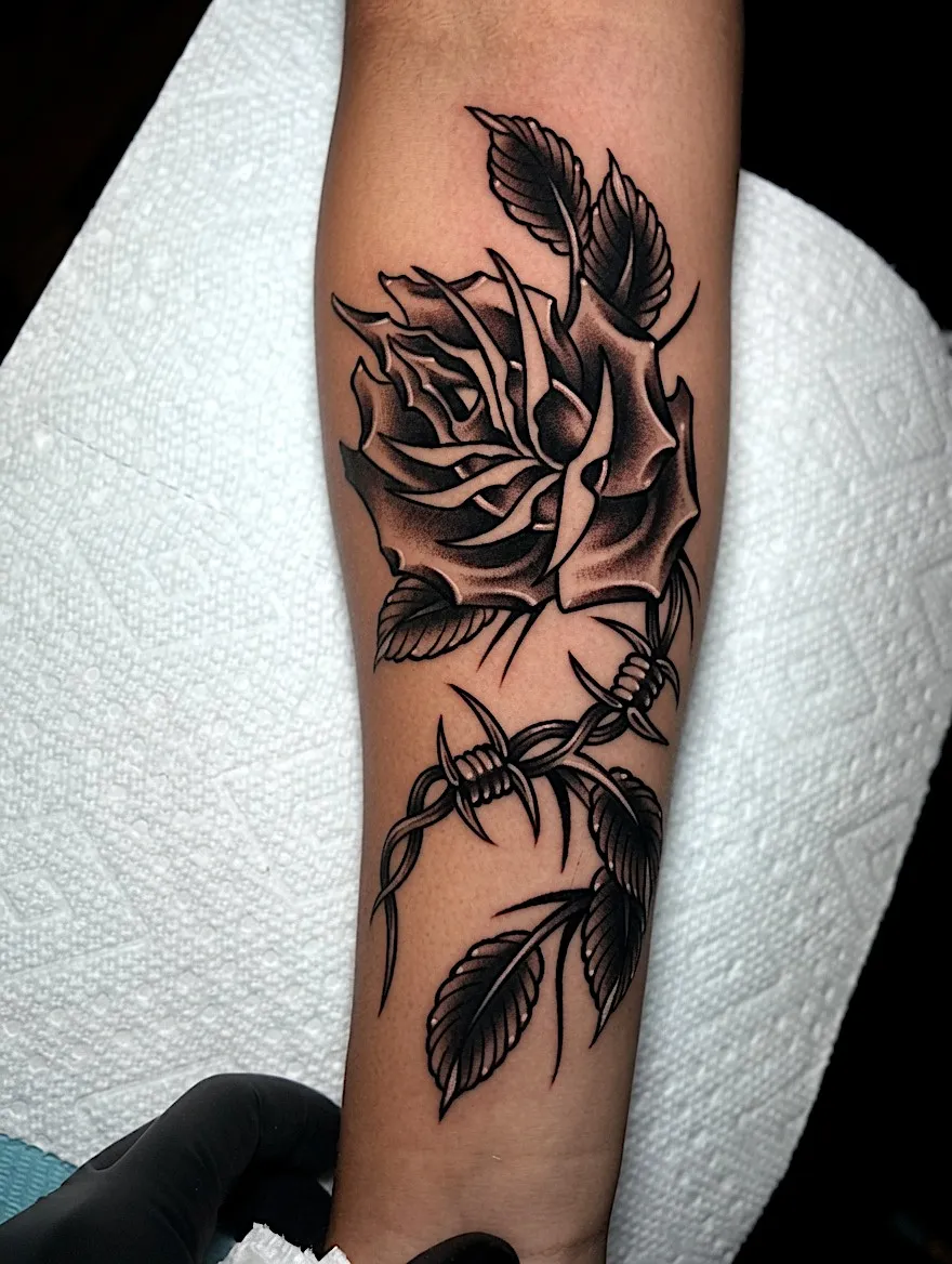 Black and grey rose tattoo intertwined with barbed wire