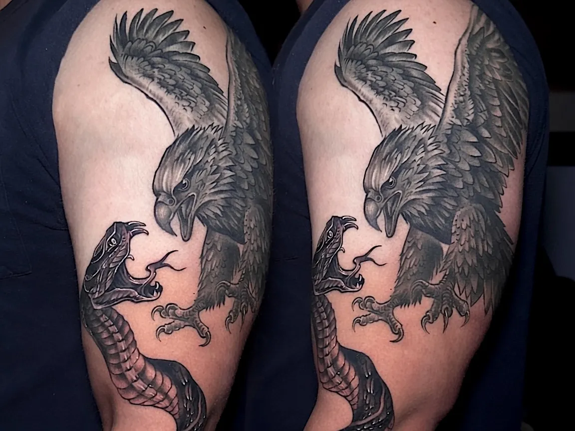 Black and grey eagle tattoo confronting a snake