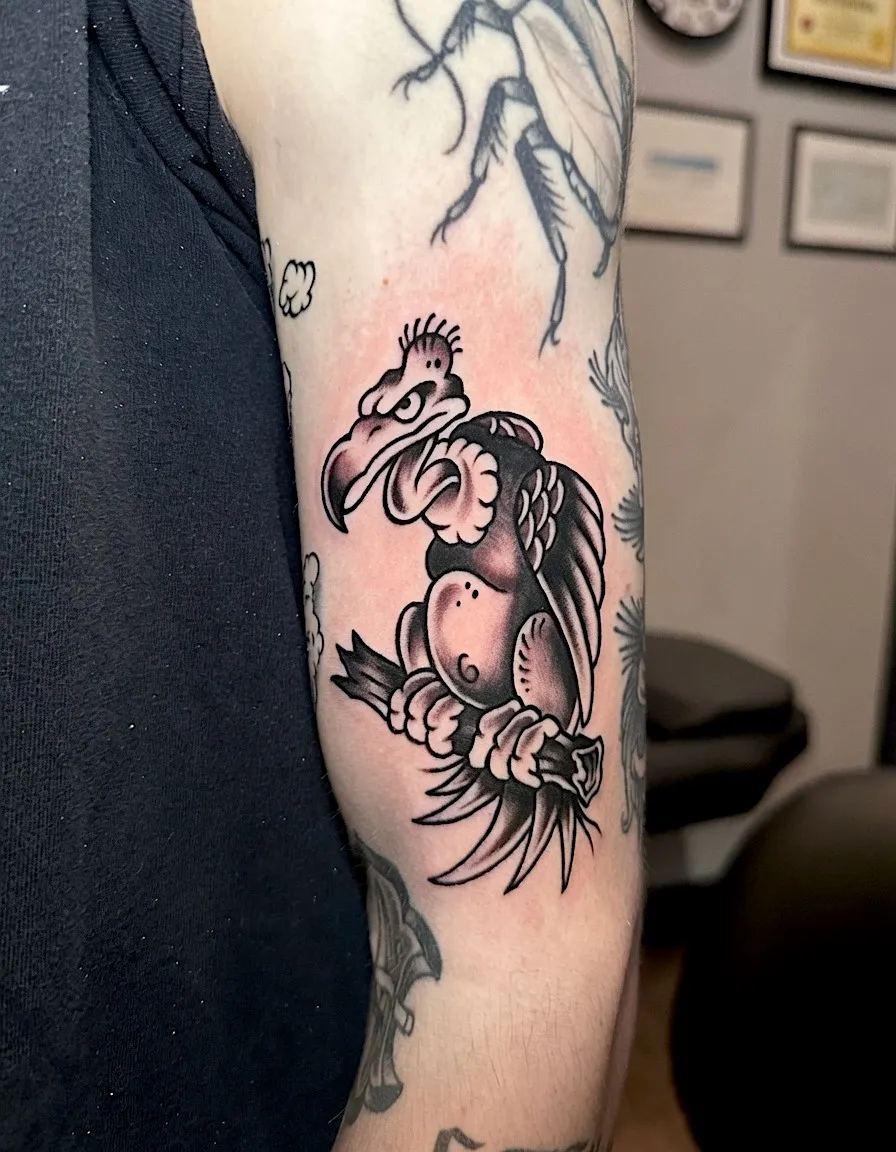 Black and grey tattoo of a long-tailed bird perched among flowers