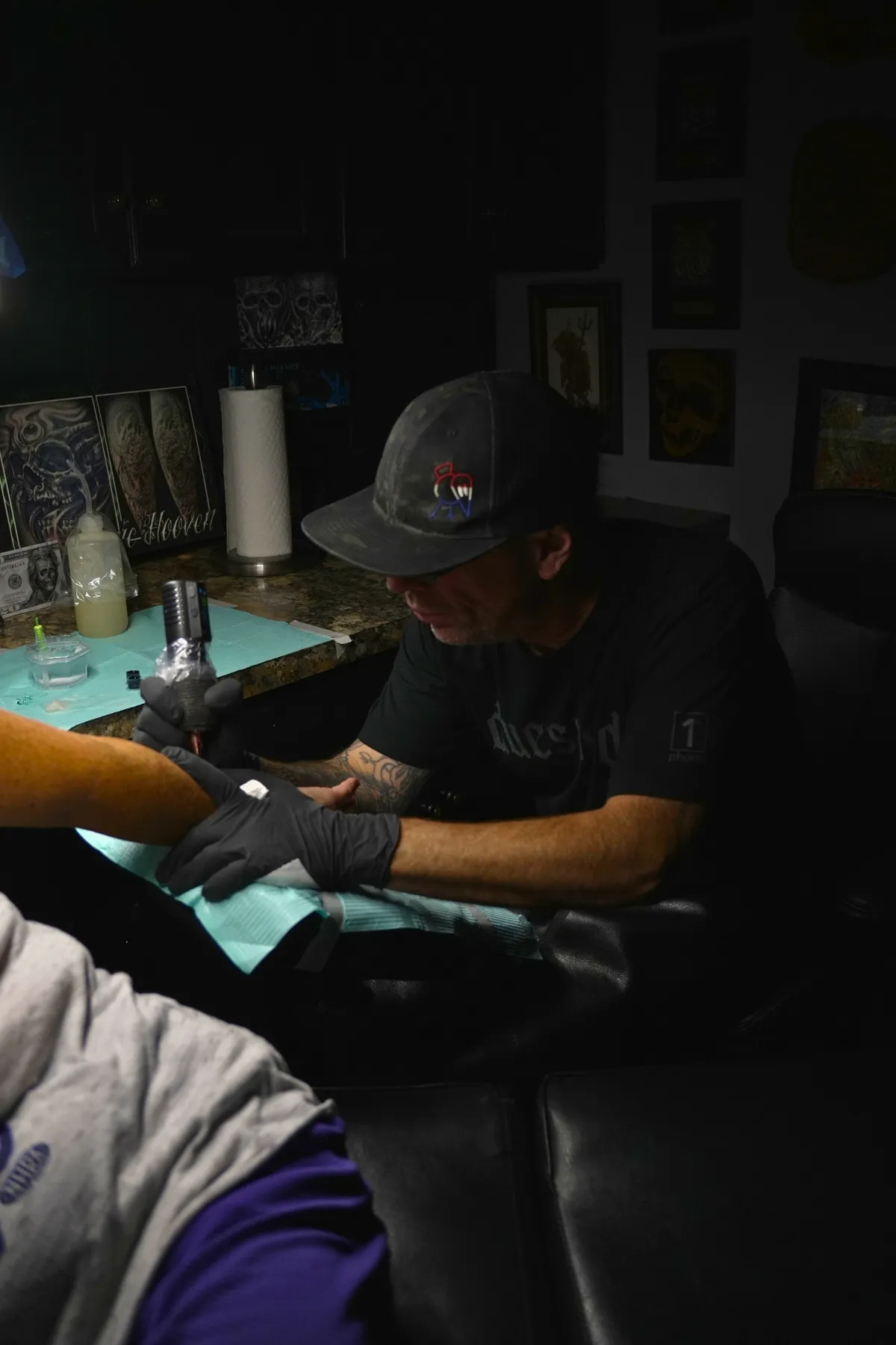 Eric Hooven tattooing a client’s arm in his studio workstation
