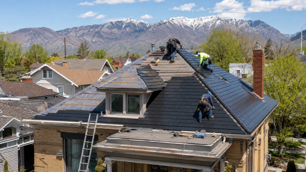 Tesla Solar Roof being installed on an older Ogden home with Wasatch peaks behind