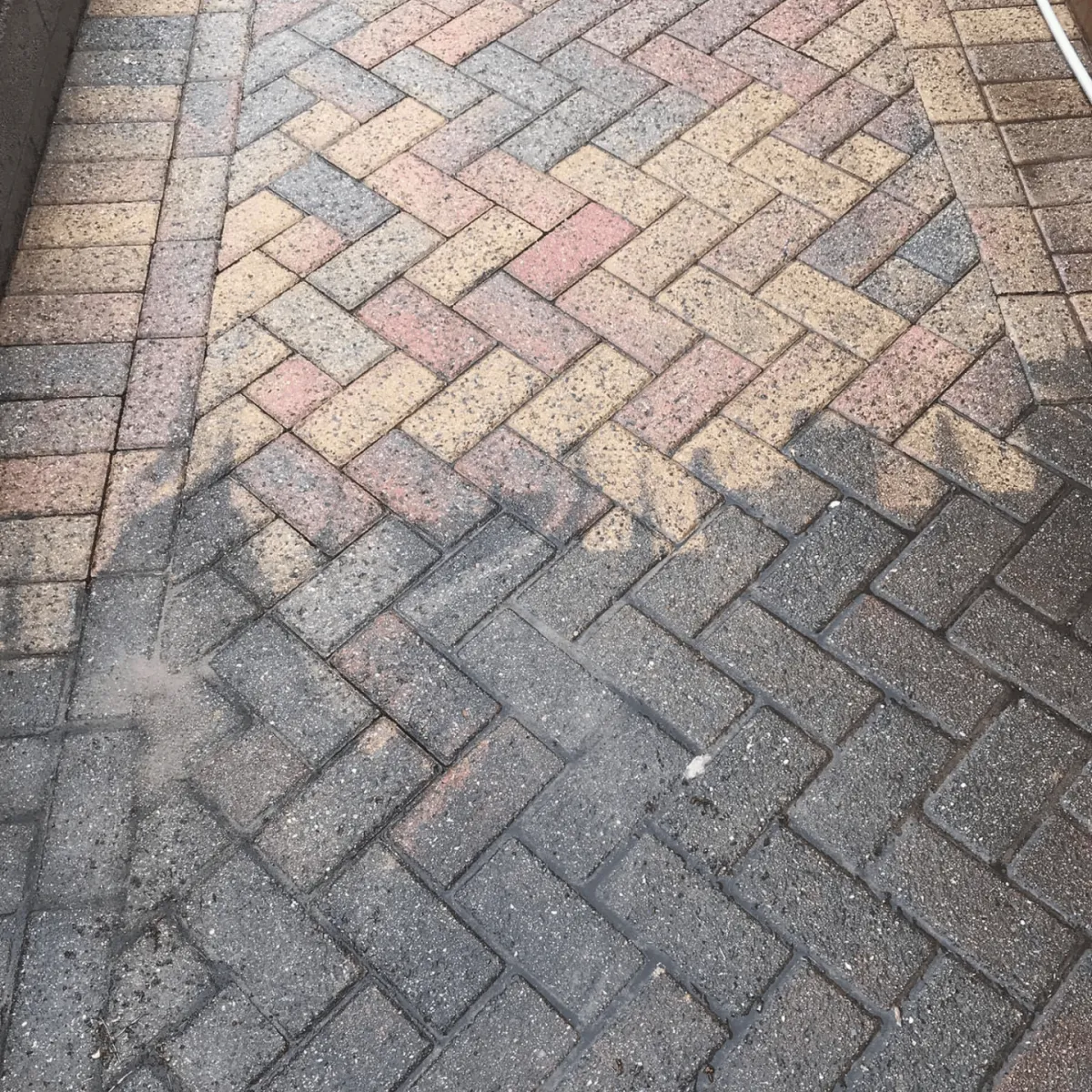 A photo of a patio where you can see the side that has been jet washed and the side that has not