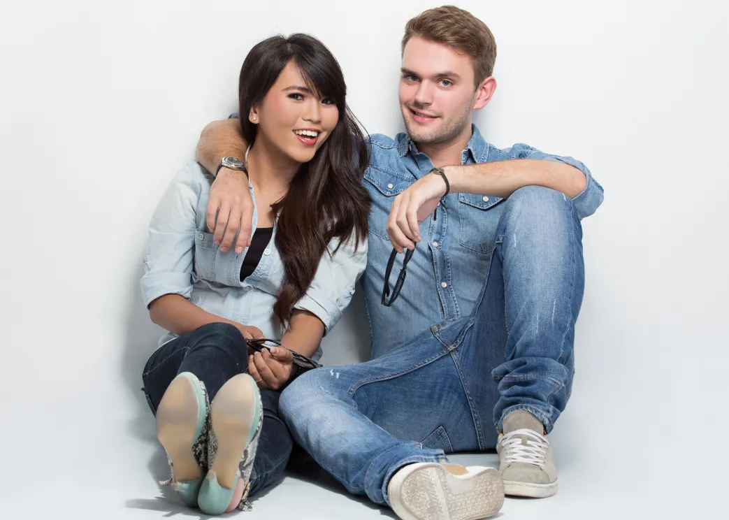A black woman wearing a light pink shirt and a person who appears to be a white male wearing a beige sweater are creating connection in their relationship on a date night.