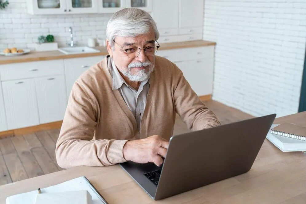 Old man enrolling to medicare sing laptop
