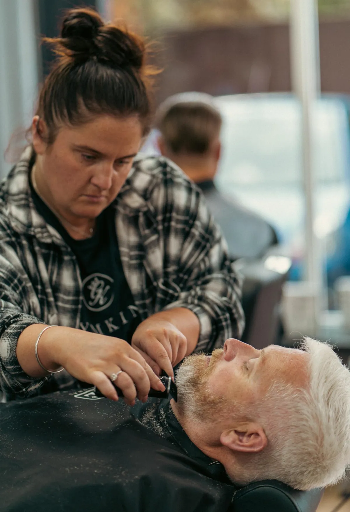 A female barber trimming a clients beard