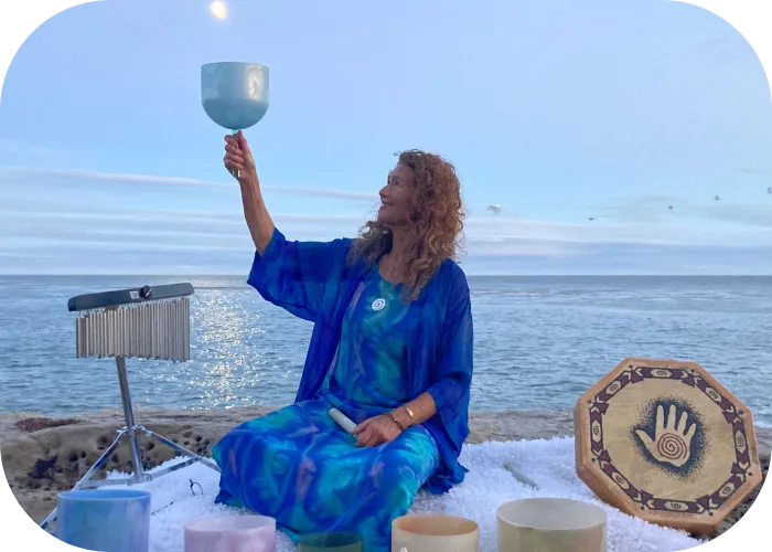 Michele Newman on the beach with crystal bowls holding cup bowl