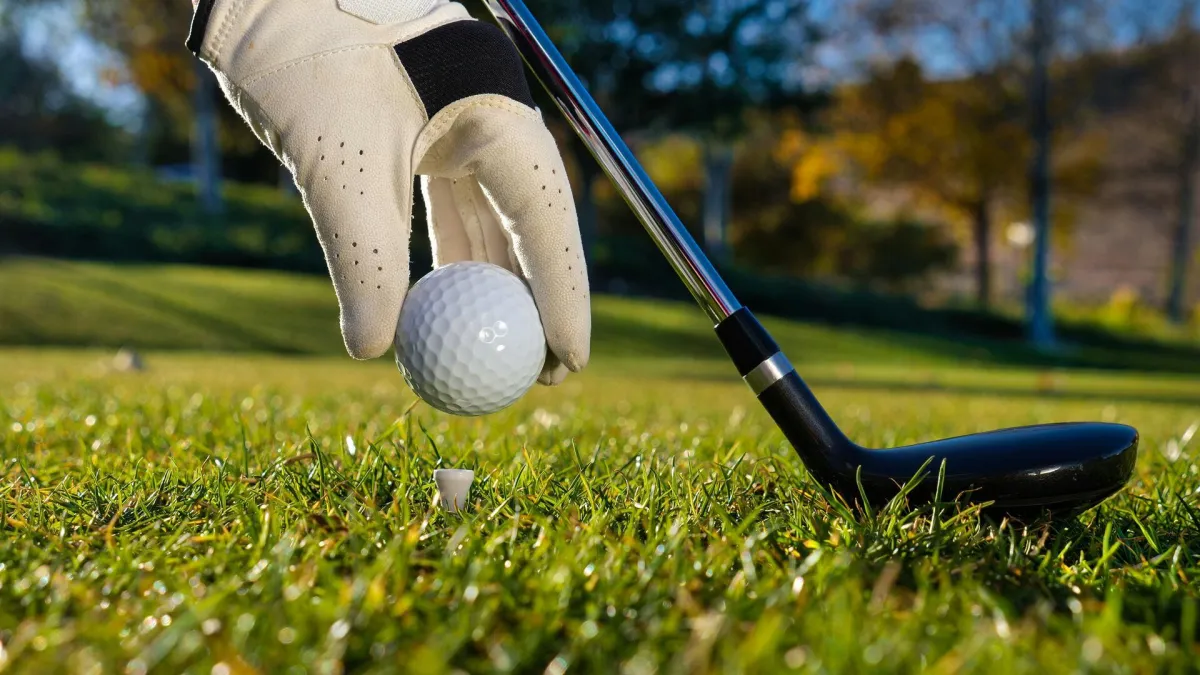 man in white shirt and blue shorts playing golf during daytime