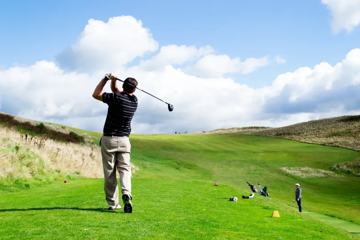man in white shirt and blue shorts playing golf during daytime