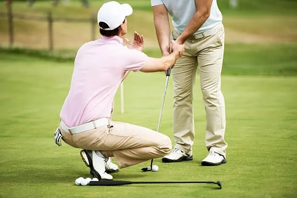 man in white shirt and blue shorts playing golf during daytime