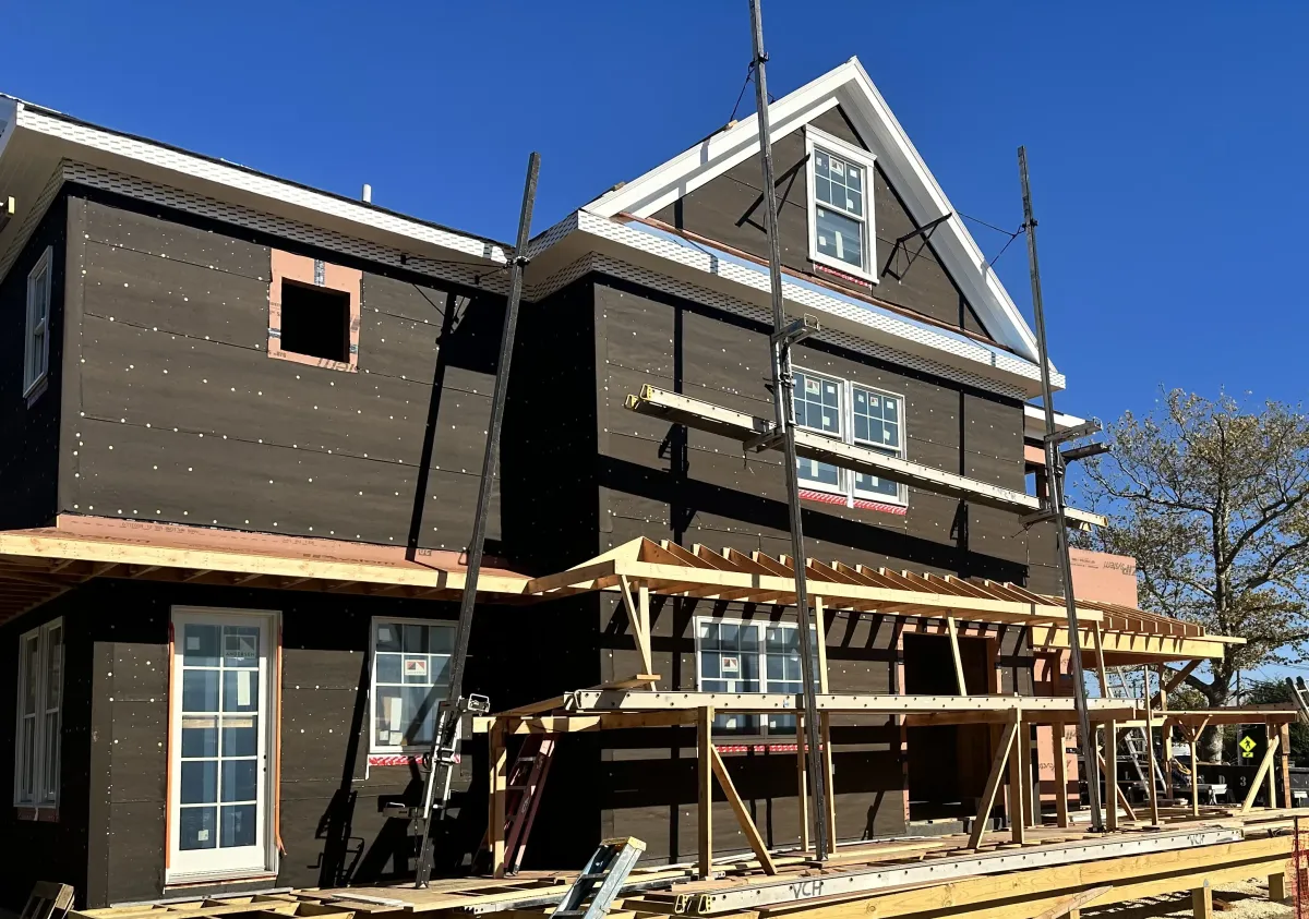 Construction worker sawing a long rectangle piece of wood in a house.