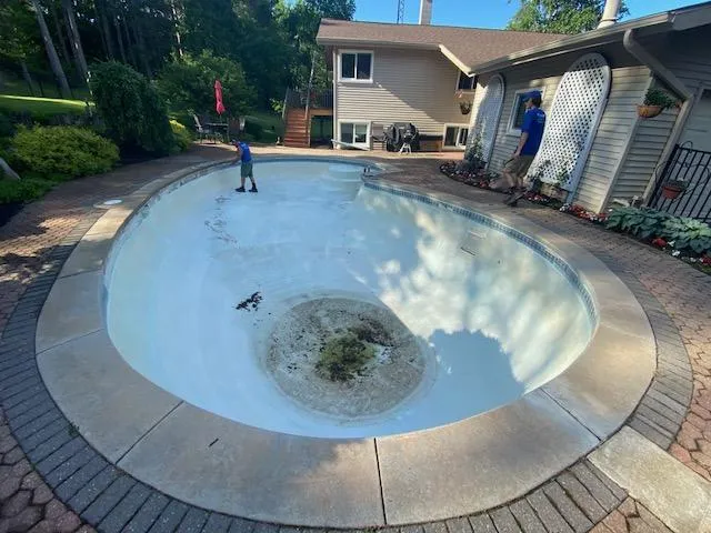 Fizer Pools technicians preparing a drained inground pool for a liner replacement in a Rockford, MI residential backyard