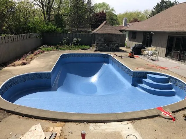 Newly installed vibrant blue vinyl pool liner in a residential inground swimming pool following a liner replacement in Rockford, MI by Fizer Pools
