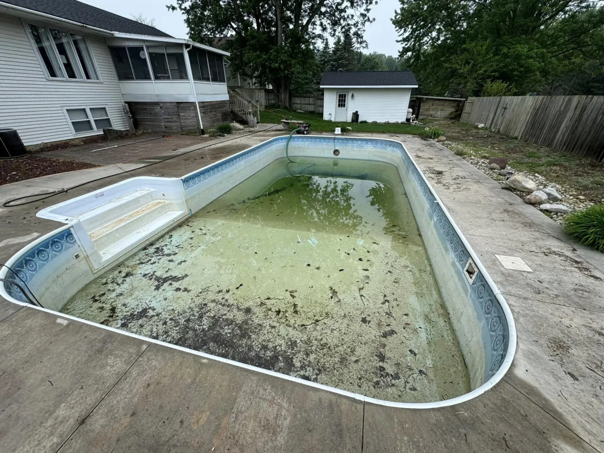 Old, green and dirty inground swimming pool with a worn liner before restoration by Fizer Pools.