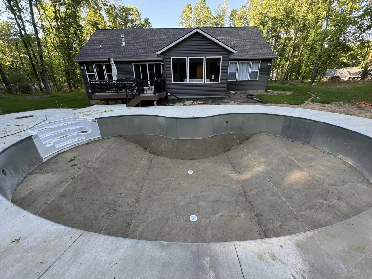 In-progress inground pool installation showing the smoothed concrete pool floor, steps, and pool deck before liner placement by Fizer Pools.