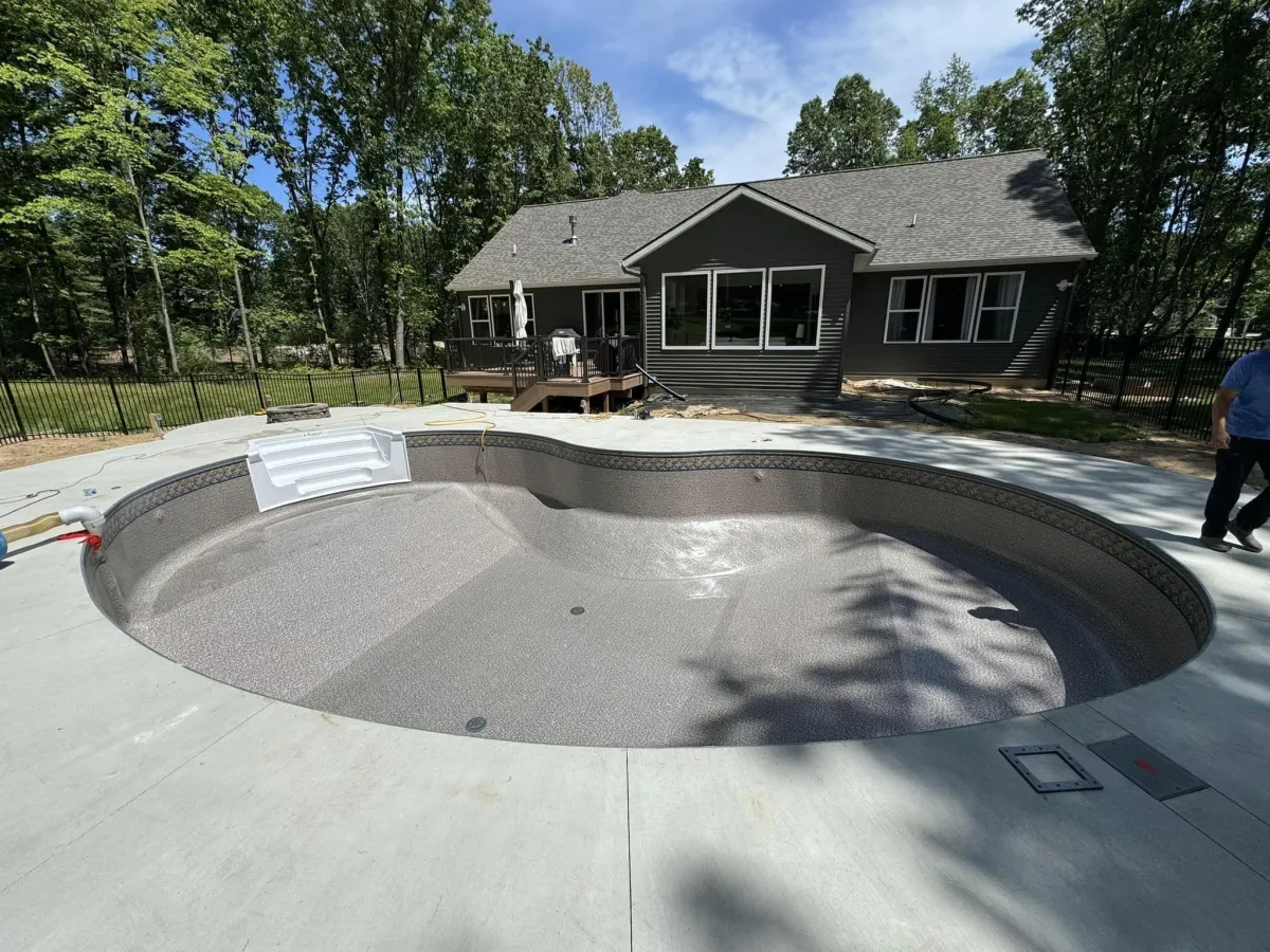 In-progress inground swimming pool installation showing prepped pool walls and concrete deck surround by Fizer Pools.