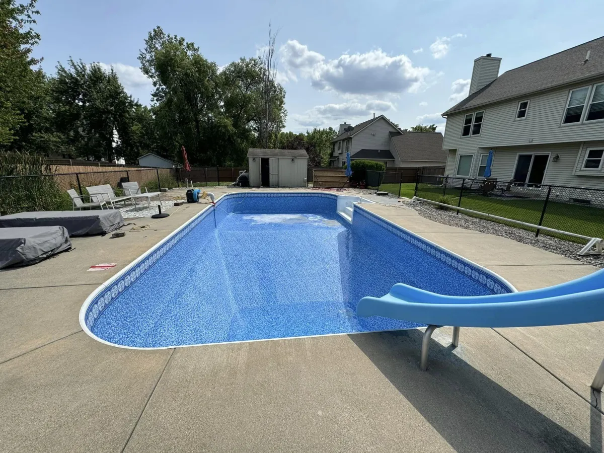 Finished inground pool restoration featuring a vibrant blue vinyl liner and concrete patio by Fizer Pools.