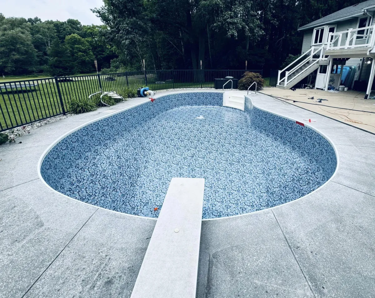 Newly installed patterned vinyl pool liner with concrete decking and diving board in Ada, MI by Fizer Pools