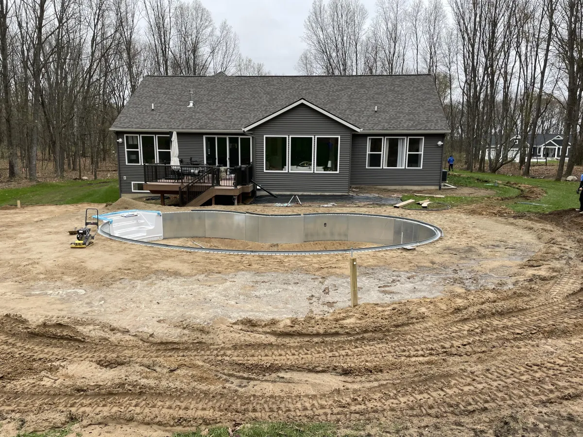 Construction phase of a new crescent-shaped inground pool installation in Rockford, MI by Fizer Pools