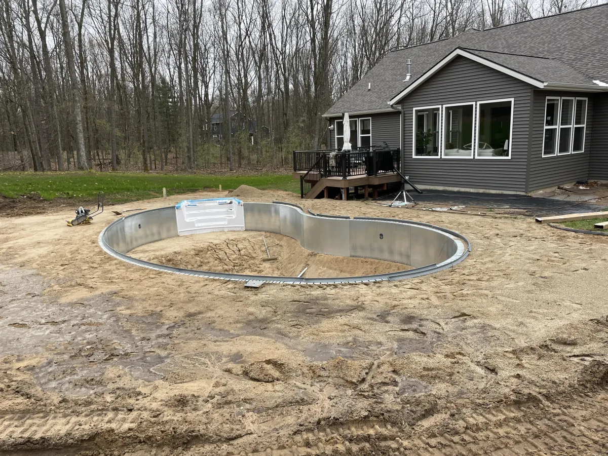 Close-up construction view of a steel-wall crescent pool installation in Rockford, MI by Fizer Pools