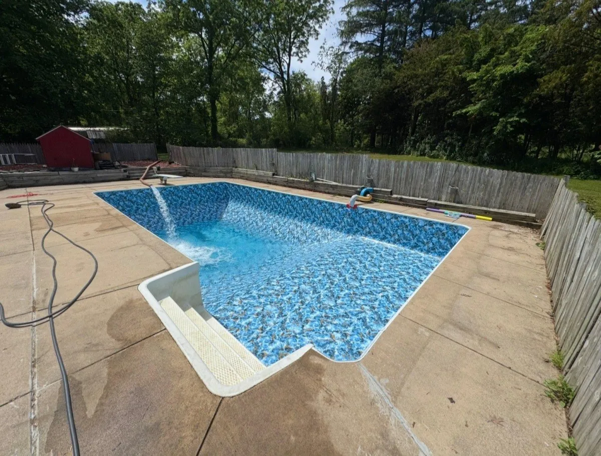 Geometric inground swimming pool with a light blue patterned liner and surrounding concrete patio