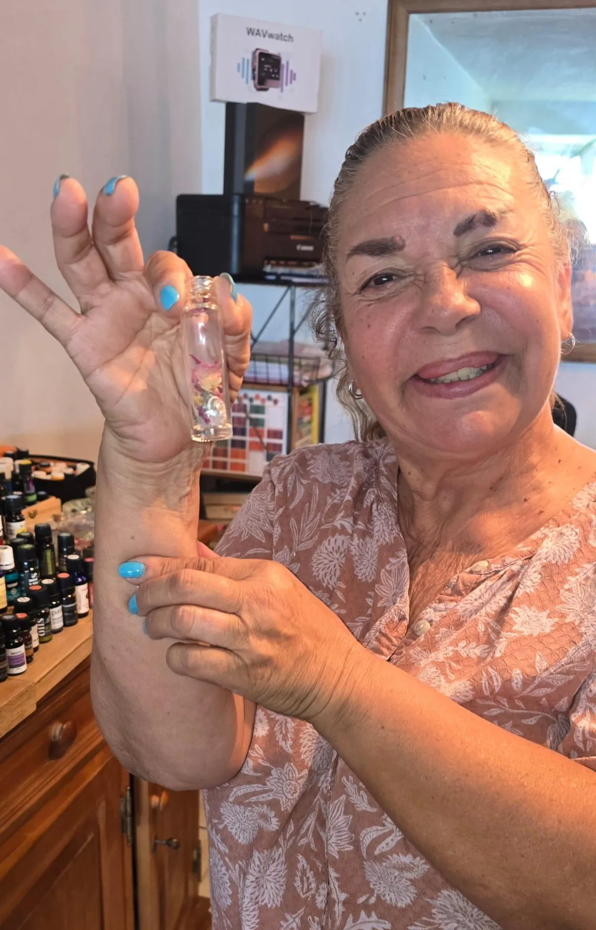 Client posing with a bottle of essential oil she made to take home from her sound healing
