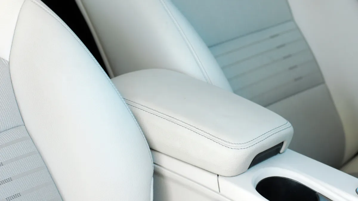 Vehicle with white upholstered seats and armrest.