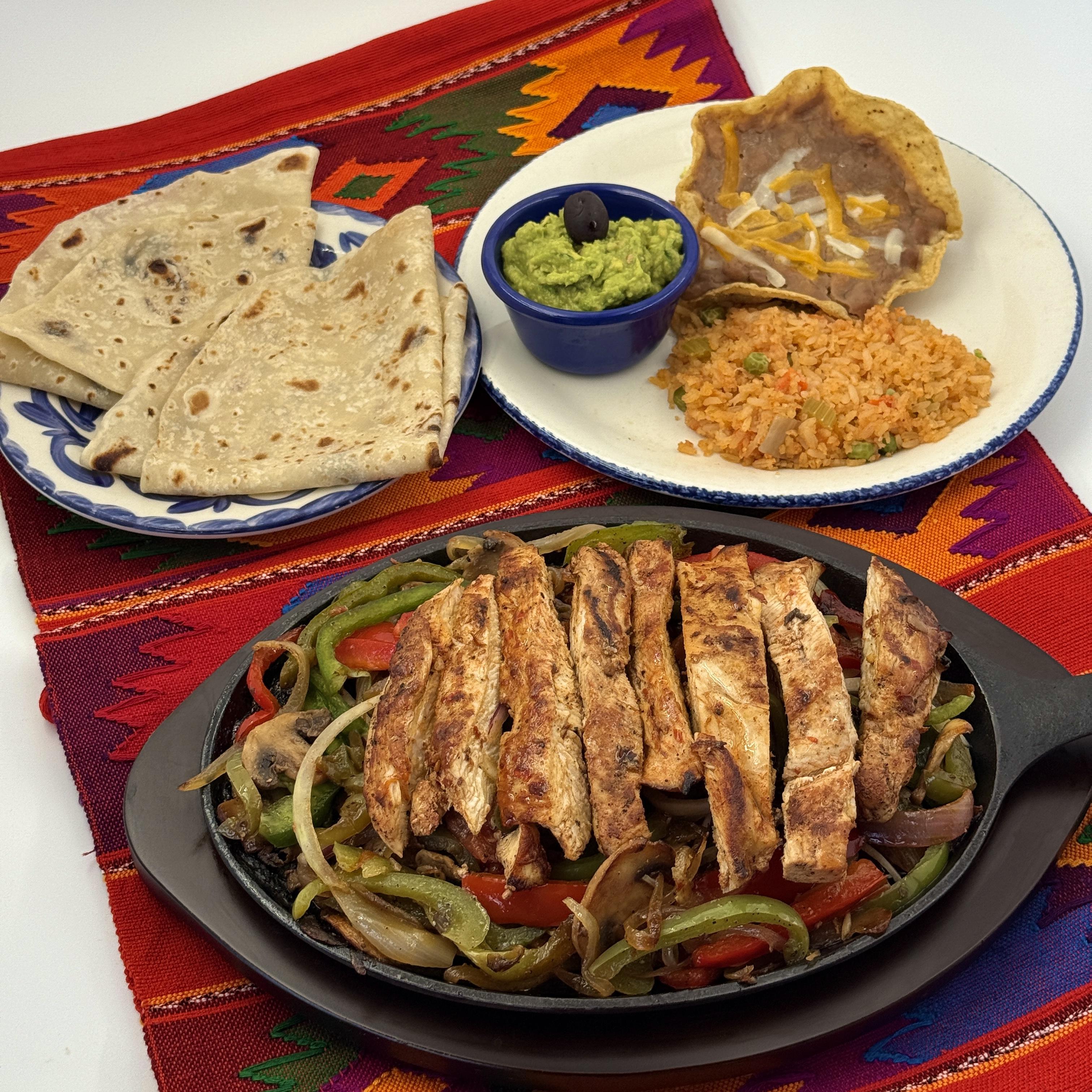 Chicken Fajitas- Flame-grilled Chicken with fresh bell peppers mushrooms, onions, and tomatoes on a sizzling skillet. Served with frijoles de la olla, guacamole, and Arroz Mexicano