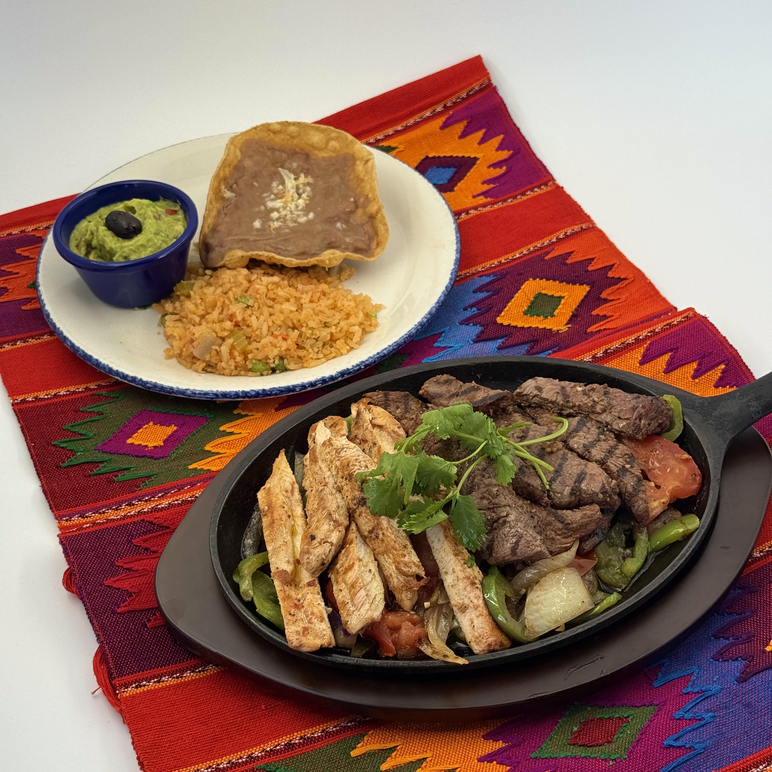 Combo Fajitas: Chicken and Beef- Flame-grilled Chicken and Beef with fresh bell peppers mushrooms, onions, and tomatoes on a sizzling skillet. Served with frijoles de la olla, guacamole, and Arroz Mexican