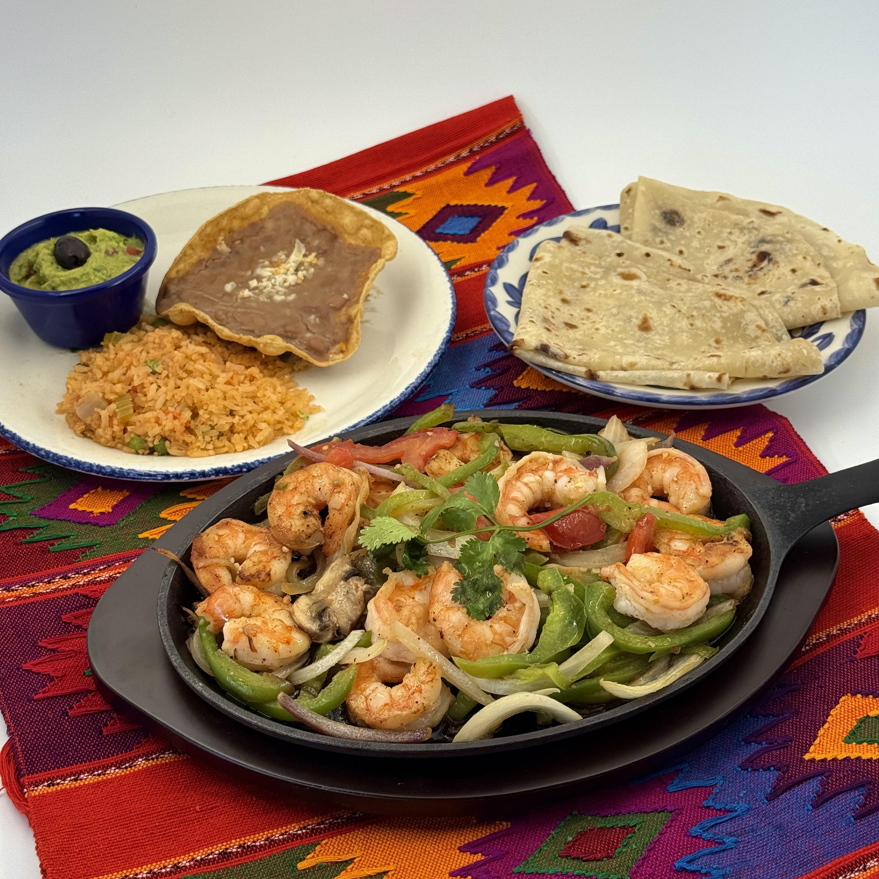 Shrimp Fajitas-Flame-grilled Shrimp with fresh bell peppers mushrooms, onions, and tomatoes on a sizzling skillet. Served with frijoles de la olla, guacamole, and Arroz Mexicano