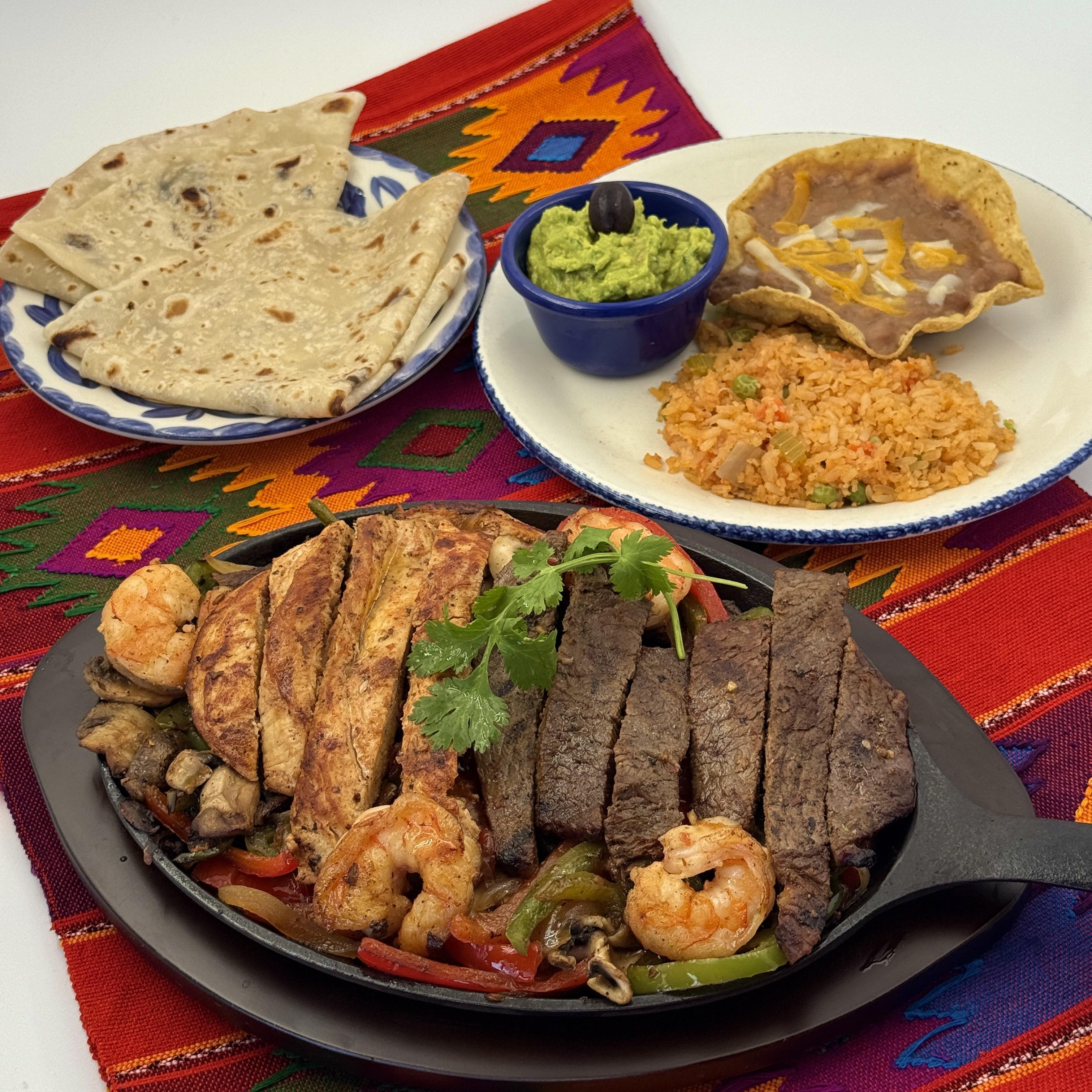 Fajitas Supremas: Chicken, Beef & Shrimp- Flame-grilled Chicken, Beef & Shrimp with fresh bell peppers mushrooms, onions, and tomatoes on a sizzling skillet. Served with frijoles de la olla, guacamole, and Arroz Mexicano