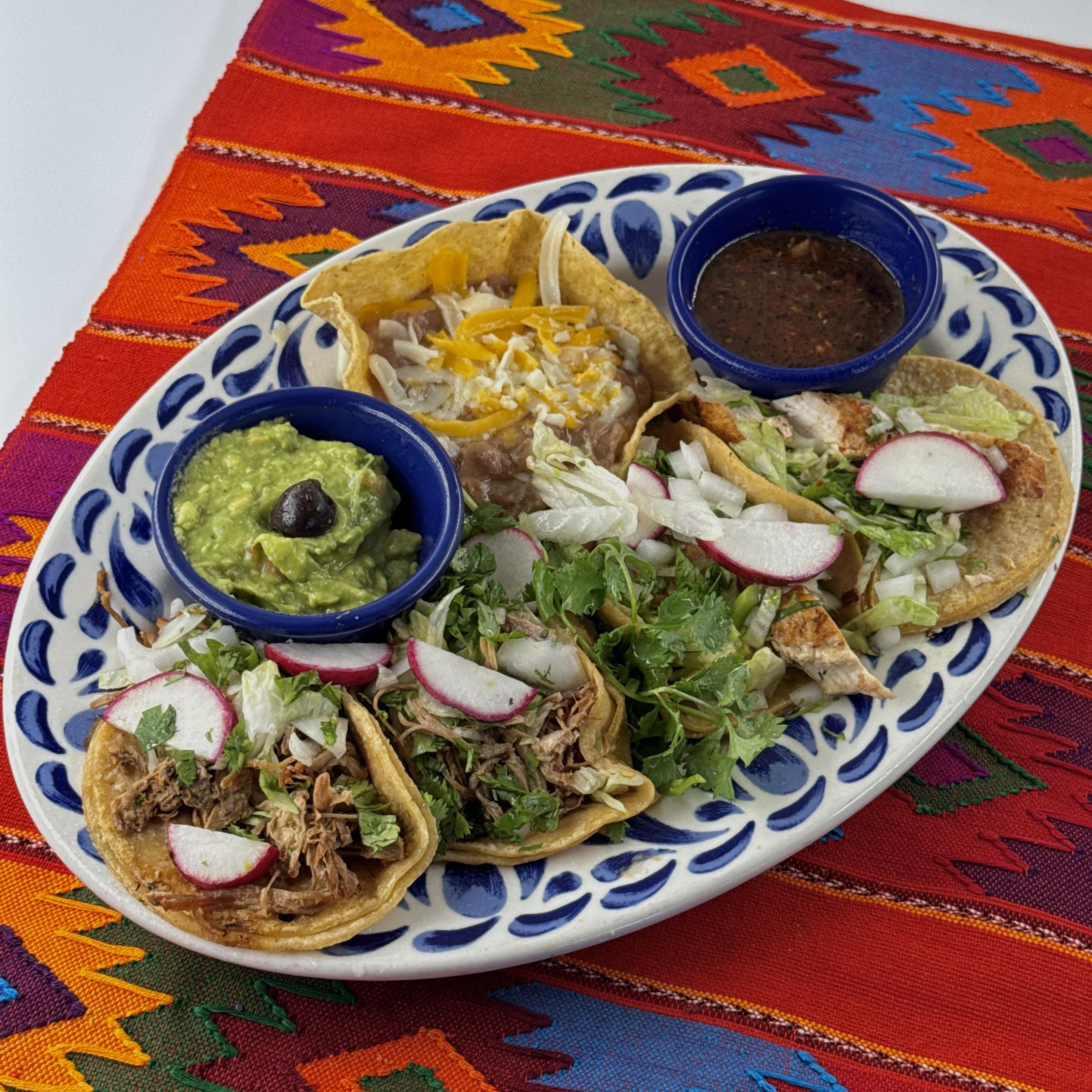 Street Tacos, Four tacos, two grilled pollo asado tacos and two grilled carnitas tacos, topped with lettuce, radishes, cilantro and onion. Served with beans, salsa quemada and guacamole on the side.