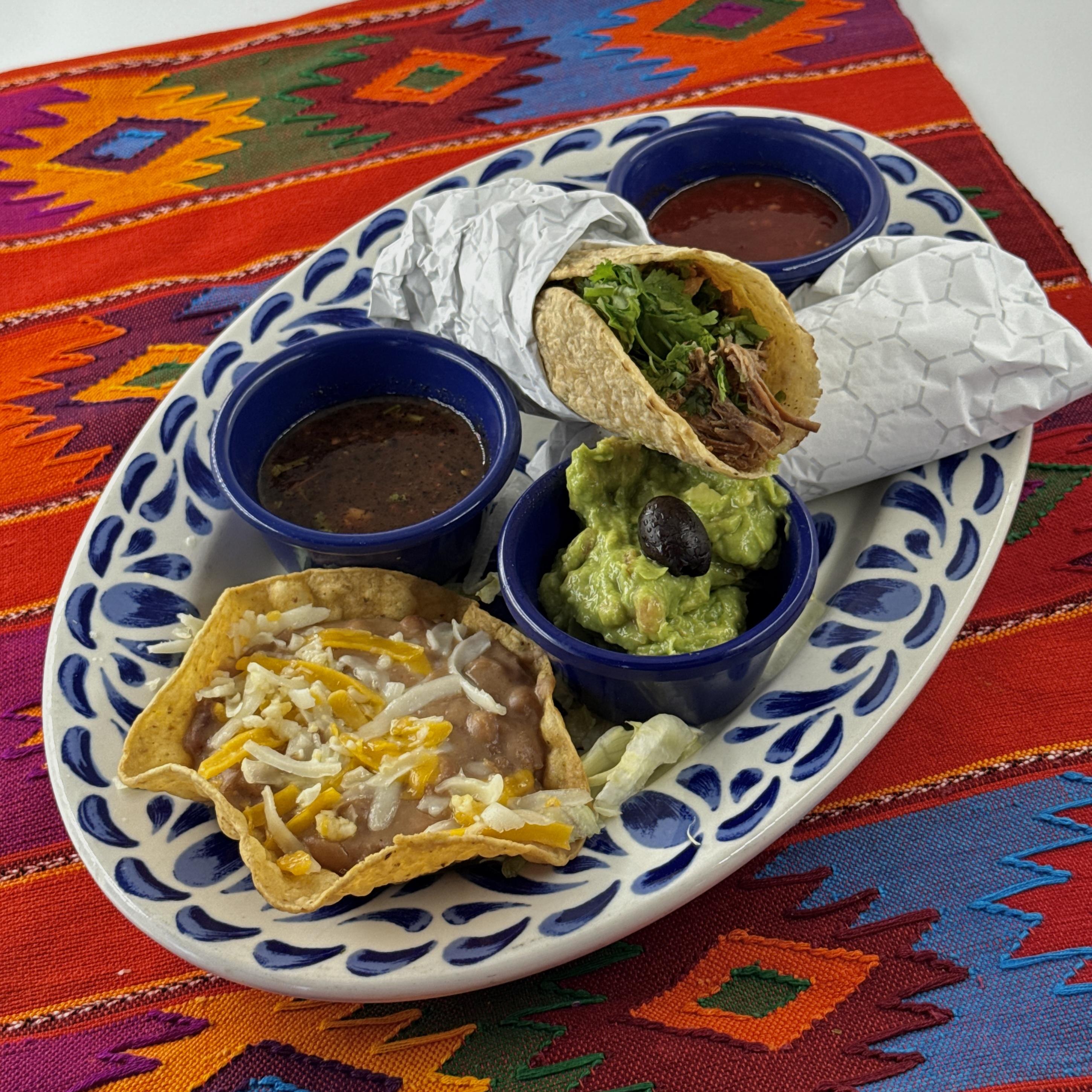 Tacos de Carnitas, Two delicious pork carnitas tacos with cilantro and onions, wrapped in warm corn tortillas. Served with three different salsas, a concha of Pico beans and guacamole.