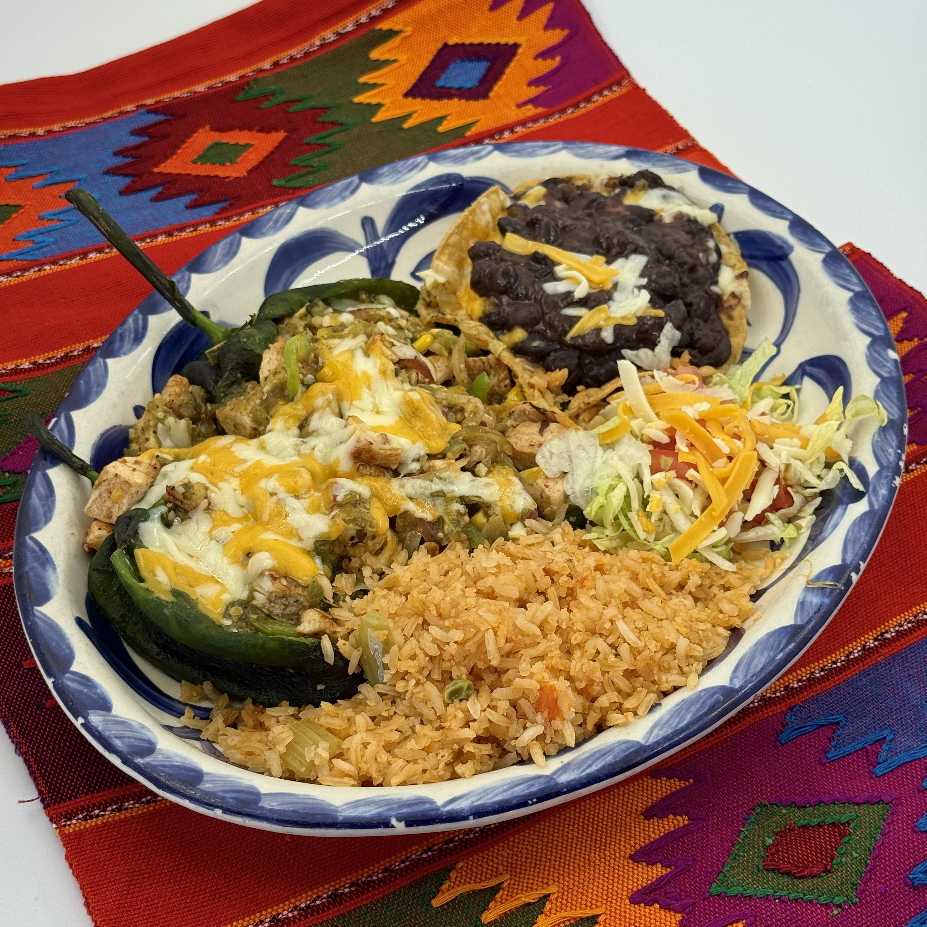 CHILE POBLANO FRESCO,Two flame roasted chiles filled with achiote seasoned vegetables and topped with creamy jalapen˜o sauce and cheese. Served with black beans.