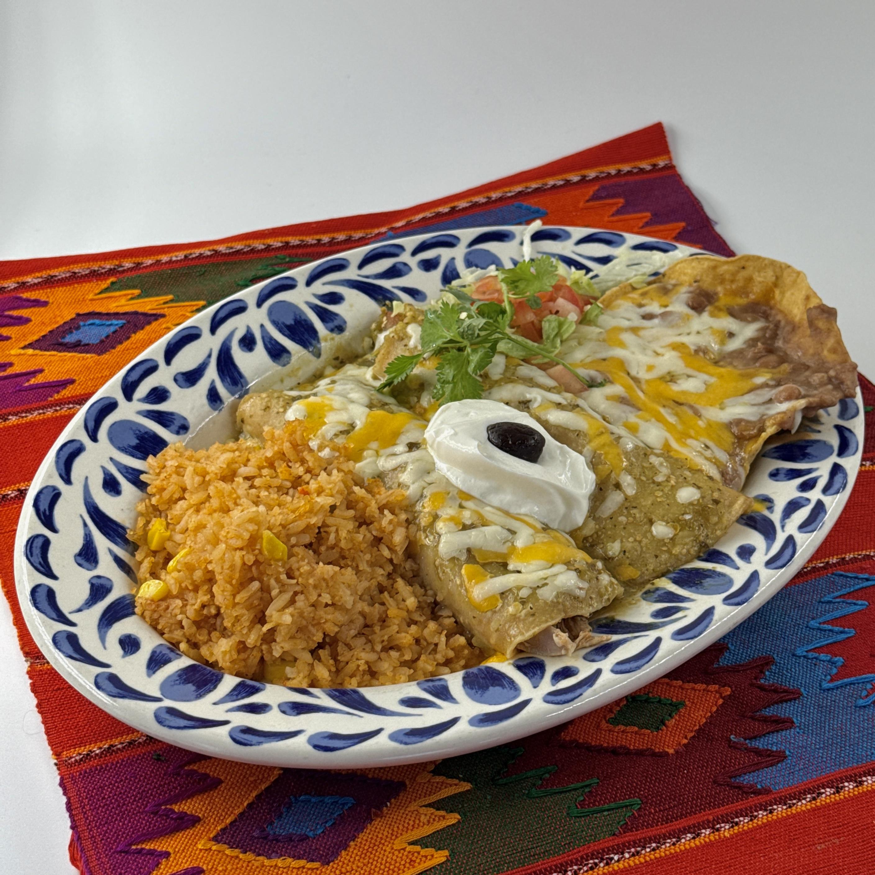 Pico Enchiladas Suizas, Enchiladas prepared with seasoned shredded chicken and green chilies, topped with salsa verde, cheese and sour cream. Served with Mexican rice and homemade beans.