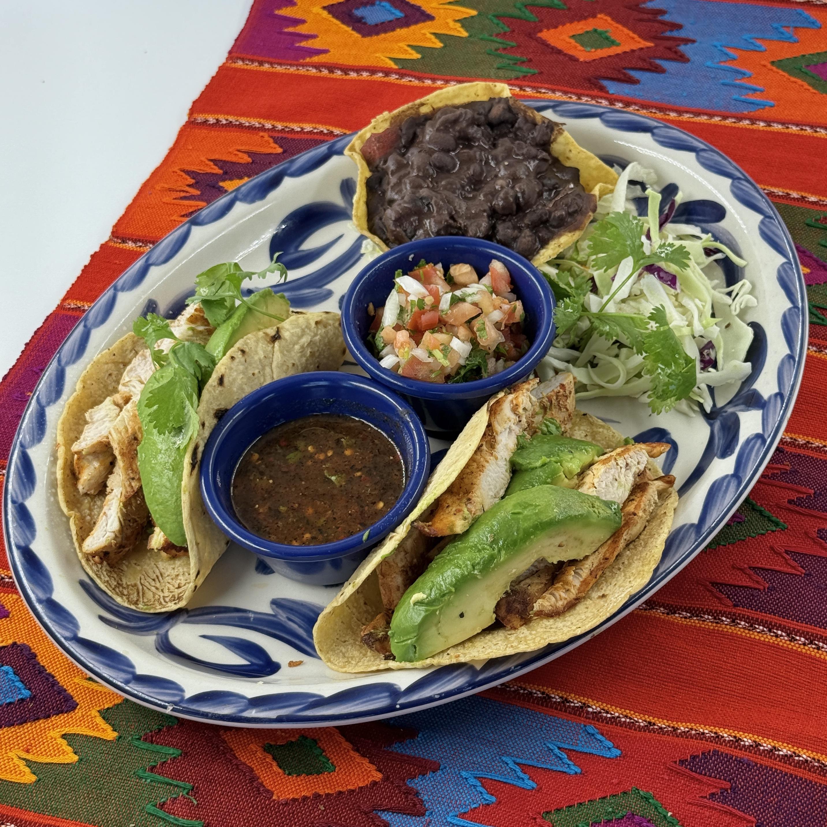 CHICKEN & AVOCADO TACOS, Two soft tacos with strips of grilled chicken breast and sliced avocado. Served with pico de gallo and black beans.
